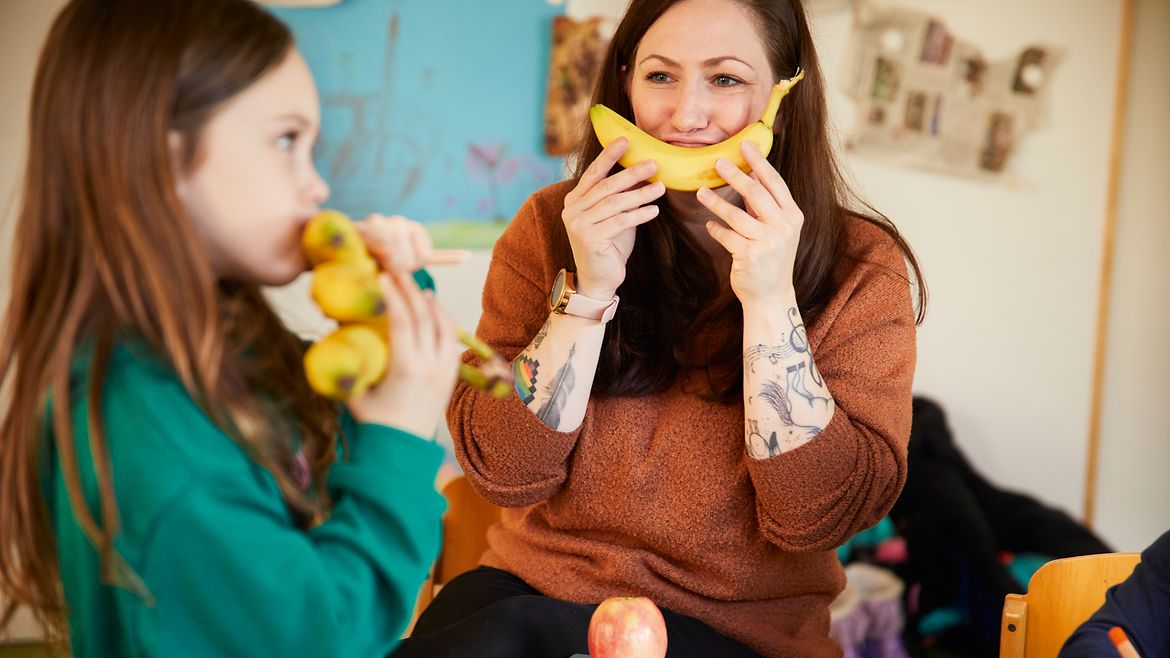 Eine Frau und ein Mädchen halten sich Bananen vor den Mund, so dass es wie ein breites Lächeln aussieht.