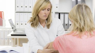 Ärztin und Patientin Eine Ärztin untersucht in einer Praxis den Arm einer Patientin